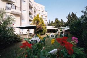 un patio con sillas, mesas, sombrilla y flores en Addar Hotel, en Jerusalén