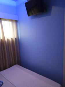 a blue bedroom with a bed and a window at Anthurium Inn in Mactan