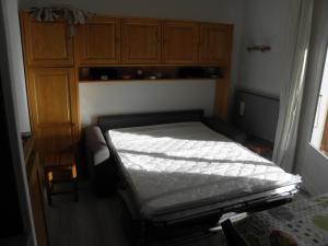 - une petite chambre avec un lit et des placards en bois dans l'établissement La Dauphinoise Alpe d'Huez, à L'Alpe-d'Huez