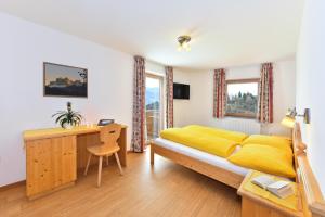 ein Schlafzimmer mit einem gelben Bett und einem Schreibtisch in der Unterkunft Saderhof in Brixen