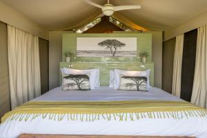 a bedroom with a large bed with a ceiling fan at Muluwa Lodge in White River