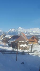 a house in the snow with mountains in the background at Drevenica Kvietok in Liptovská Kokava