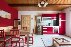 una cucina con armadi rossi, tavolo e sedie di Apartma Angelca a Kranjska Gora
