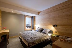 een slaapkamer met een bed met een houten muur bij Odalys Chalet Nuance de gris in L'Alpe-d'Huez