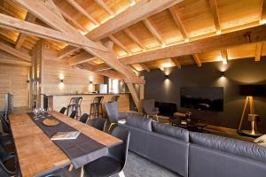 a dining room with a long table and a couch at Odalys Chalet Nuance de bleu in L'Alpe-d'Huez