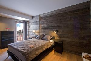Un dormitorio con una pared de madera y una cama en Odalys Chalet Nuance de blanc, en L'Alpe-d'Huez