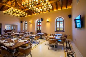 a dining room with tables and chairs and chandeliers at Mystras Grand Palace Resort & Spa in Mystras