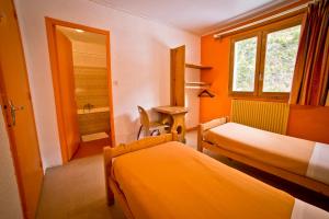 Cette chambre comprend deux lits, un bureau et un miroir. dans l'établissement Centre de Vacances Le Val d'Escreins, à Vars 27 autres photos