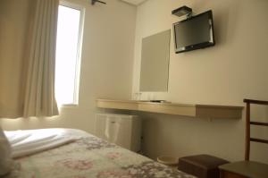 a bedroom with a bed and a tv on the wall at Crigial Hotel in Jaguarão