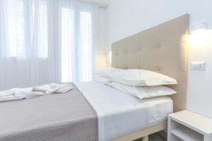 a white bedroom with a bed with white pillows at Hotel Tourist Meuble in Rimini