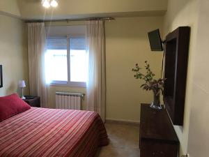 a bedroom with a bed and a television and a vase with flowers at Casa Monte Hermoso Del Este in Monte Hermoso