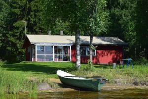 a boat in the water in front of a house at Karjalan Helmi in Tolosenmäki