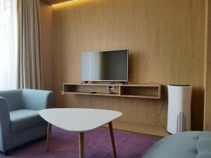 a living room with a tv and a chair and a table at City Park Hotel in Skopje