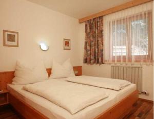 Schlafzimmer mit einem Bett mit weißer Bettwäsche und einem Fenster in der Unterkunft Ferienwohnungen Haaser in Maurach