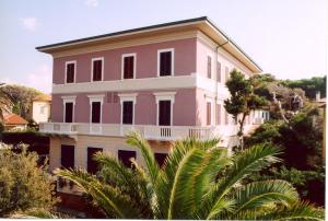 un edificio rosa y blanco con una palmera delante en La Perla, en Castiglioncello
