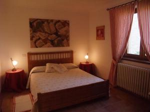 ファブロにあるAgriturismo Pian di Frattinaのベッドルーム1室(ベッド1台、テーブルにランプ2つ付)