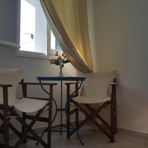 una mesa con dos sillas y un jarrón con flores. en Agkira Studios Milos, en Provatas