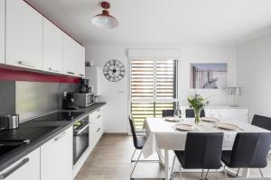 - une cuisine blanche avec une table et des chaises dans l'établissement Le Garden by Cocoonr, à Dinard