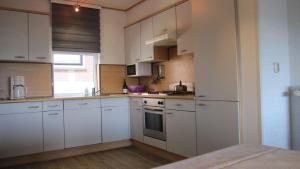 a white kitchen with white cabinets and a window at paNOORama appartementen in Noorbeek