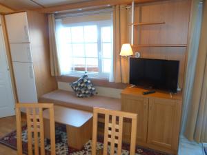 a living room with a table and a tv and a window at Mobilheim Seezauber in Uttendorf