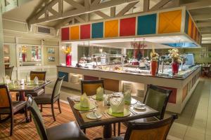 a restaurant with tables and chairs and a kitchen at Peermont Walmont at the Grand Palm, Gaborone in Gaborone