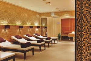 a waiting room with a row of couches and tables at H+ Hotel Hannover in Hannover