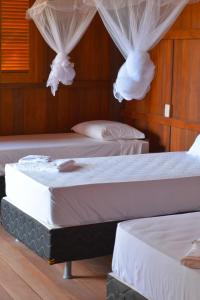 two beds in a room with white drapes at Casa Dunas da Barrinha in Barrinha