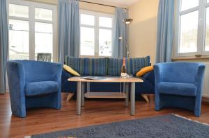 ein Wohnzimmer mit blauen Stühlen und einem Tisch in der Unterkunft Villa Seerose - Appartement 07 in Ostseebad Sellin