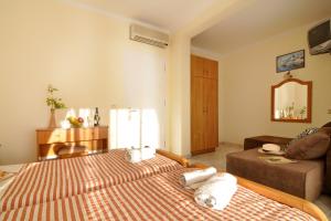 1 dormitorio con 2 camas, sofá y espejo en Lido Sofia Holidays en Agios Gordios