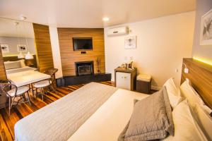 ein Hotelzimmer mit einem Bett und einem Esszimmer in der Unterkunft Hospedaria das Brisas in Praia do Rosa
