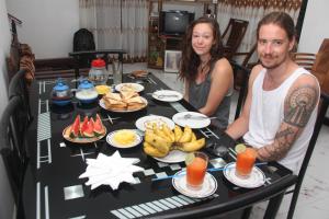 Un uomo e una donna seduti a un tavolo con del cibo di Maneesha Guest House a Weligama