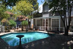 a swimming pool with chairs in front of a house at Hobbit Boutique Hotel in Bloemfontein