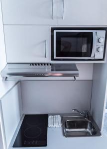 a small kitchen with a microwave and a sink at FirstSleep Boardinghouse Griesfeldstrasse München in Munich