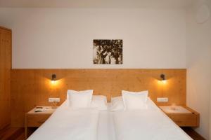 une chambre avec un grand lit blanc avec deux tables dans l'établissement Schwarzplatterhof, à Merano