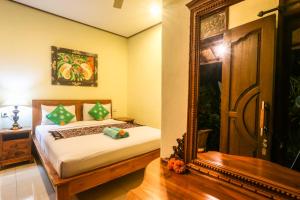 um quarto com uma cama e um espelho grande em Gusti Kaler House em Ubud