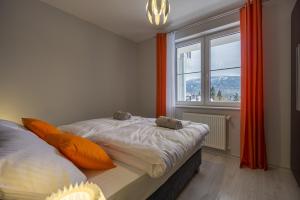 sypialnia z łóżkiem z pomarańczowymi poduszkami i oknem w obiekcie Villa Mountain View Apartamenty w Szklarskiej Porębie