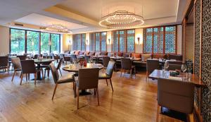 a dining room with tables and chairs and windows at Boutique Hotel Poppenbütteler Hof in Hamburg