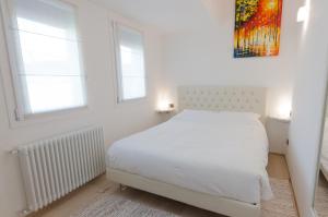 ein weißes Schlafzimmer mit einem Bett und zwei Fenstern in der Unterkunft Corte Maggiore in Ravenna