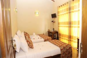 a hotel room with two beds and a television at Lake View Hotel & Bungalow(pvt) Ltd in Nuwara Eliya