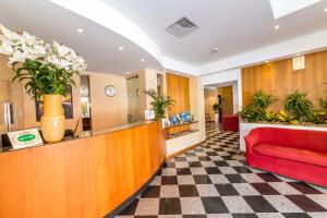 una sala d'attesa con un divano rosso e fiori di Hotel Villa Gioiosa a Lido di Jesolo