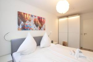 een slaapkamer met een wit bed met witte kussens bij Sylter-Rose-Haus-Ankerlicht-Wohnung-72 in Westerland