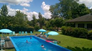 una piscina con personas en un patio con sombrillas en Villa Sophia del Delta (Cabañas en la Isla-Tigre) en Tigre