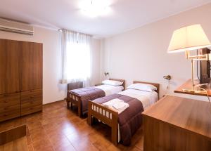 a hotel room with two beds and a dresser at Il Novecento in Casarsa della Delizia