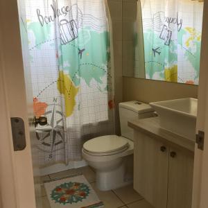 a bathroom with a toilet and a sink and a shower curtain at Casa Los Robles in Pucón