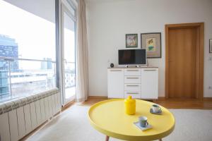 a living room with a yellow table and a tv at Michelle Apartment in Sofia