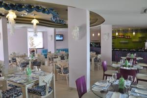 a restaurant with white tables and purple chairs at Hotel Isla Verde in Tubará