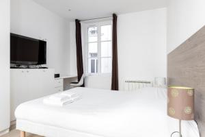 - une chambre blanche avec un lit et une télévision dans l'établissement Appartement Arlequin / Chardonnay, à Paris