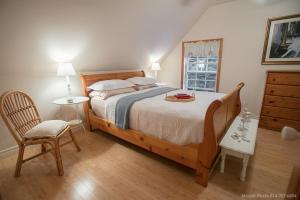 a bedroom with a large bed and a chair at La Maison Bleue du Lac Wallace in Coaticook