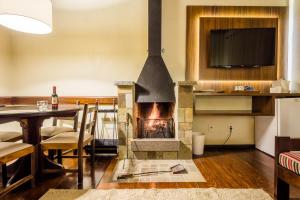 a fireplace in a living room with a table and a dining room at Vila Suzana Parque Hotel in Canela