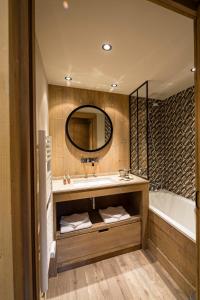 a bathroom with a sink and a tub and a mirror at Hotel Kandahar in Val dʼIsère